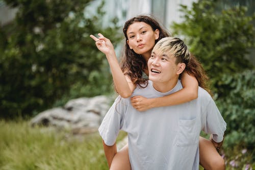 快乐的民族小伙子背着女朋友在公园里 · 免费素材图片