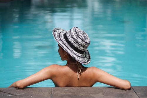 匿名苗条的女士在游泳池水中休息，看着别处 · 免费素材图片