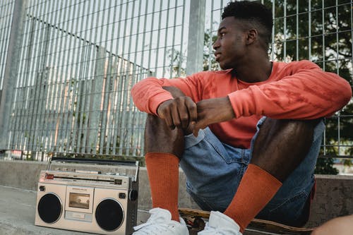 坐在船上听在录音机上的音乐的男人微笑着 · 免费素材图片