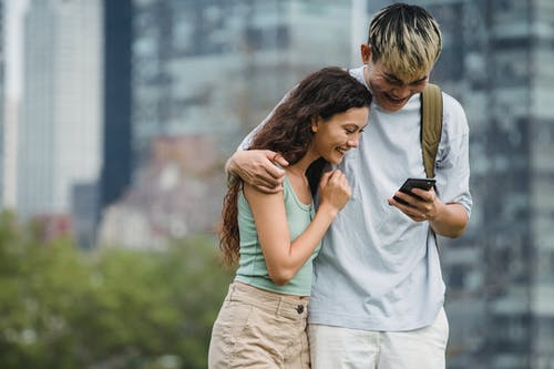 看着智能手机在城市街道上的多种族对幸福的夫妻 · 免费素材图片