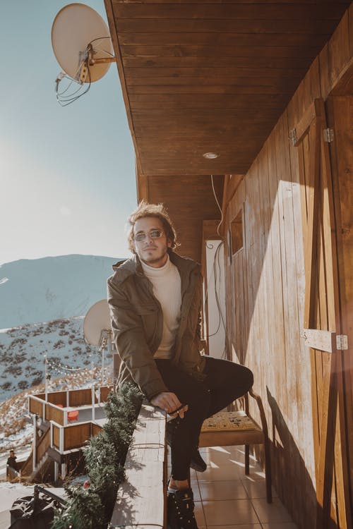 男子坐在木栅栏上的照片 · 免费素材图片