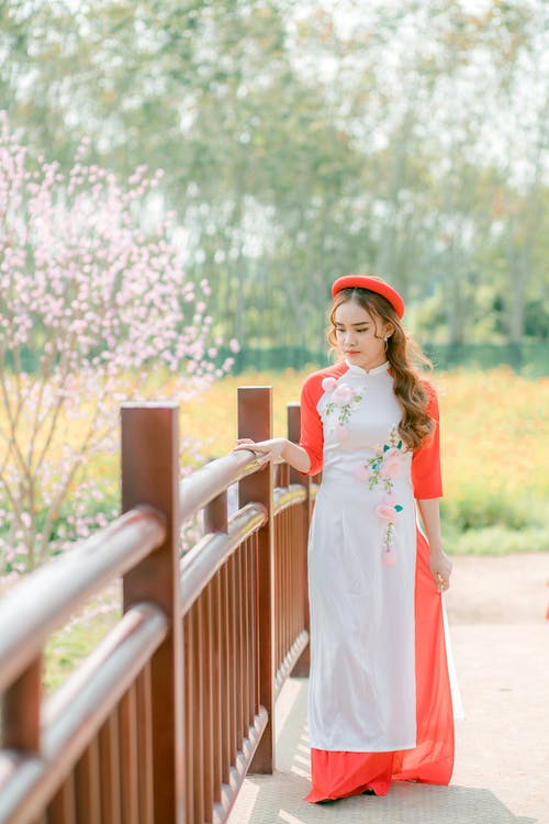 白色和橙色的花裙子，站在一座木桥上的女人 · 免费素材图片