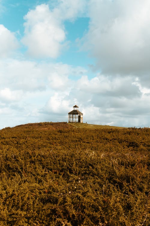 白色和黑色的灯塔，在白云和蓝天下的棕色草地上 · 免费素材图片
