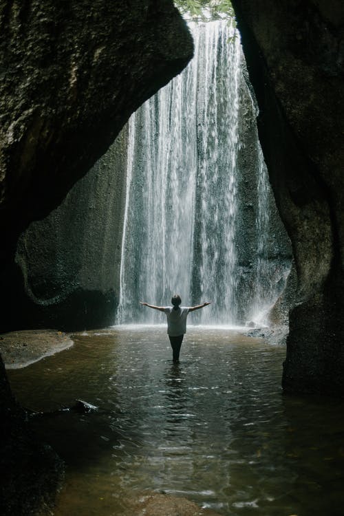 不可识别的女人站在峡谷与瀑布 · 免费素材图片