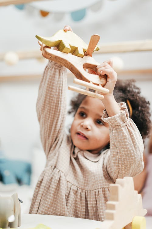 女孩抱着木制玩具 · 免费素材图片