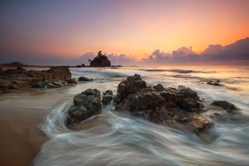 日落期间在海边的石头 · 免费素材图片