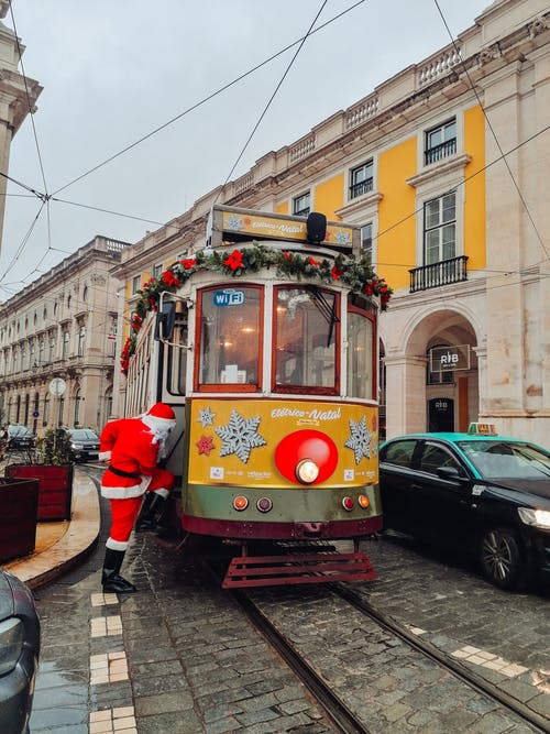 圣诞老人即将进入建筑物旁边的黄色电车 · 免费素材图片