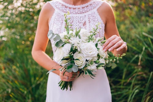 拿着白玫瑰花束的白花无袖连衣裙的女人 · 免费素材图片