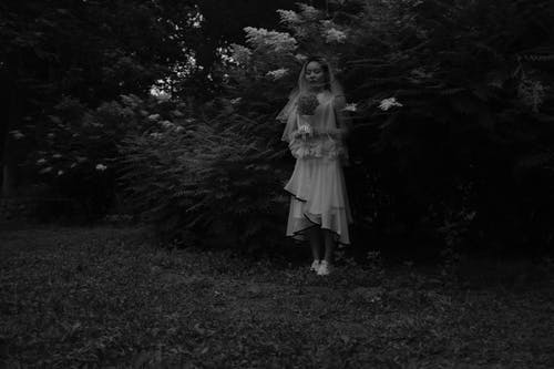 女人在植物旁边抱着花束的灰度照片 · 免费素材图片