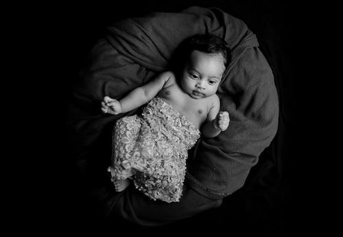 婴儿躺在毯子上的灰度照片 · 免费素材图片