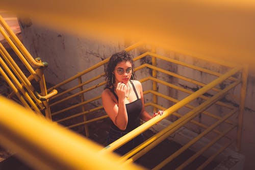 黑色背心和黑色的裤子，站在黄色的金属楼梯上的女人 · 免费素材图片