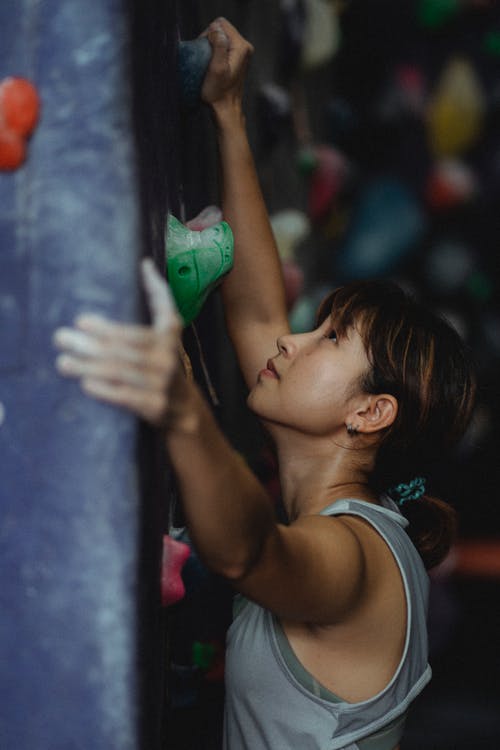 在现代健身房集中亚裔女子攀岩墙 · 免费素材图片
