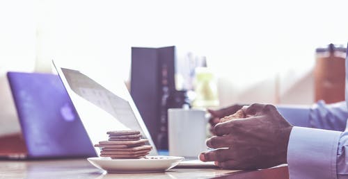 男子倚在桌上用白色碟上的饼干堆 · 免费素材图片