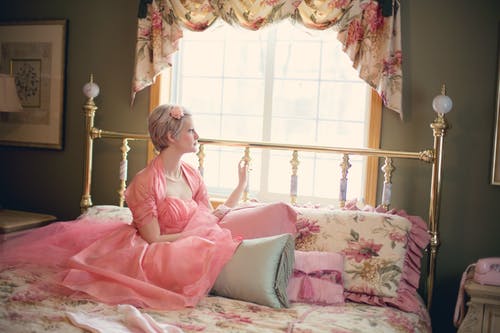 女人坐在窗边的床上 · 免费素材图片