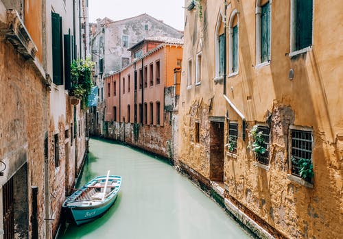 在混凝土建筑之间的河上划船 · 免费素材图片