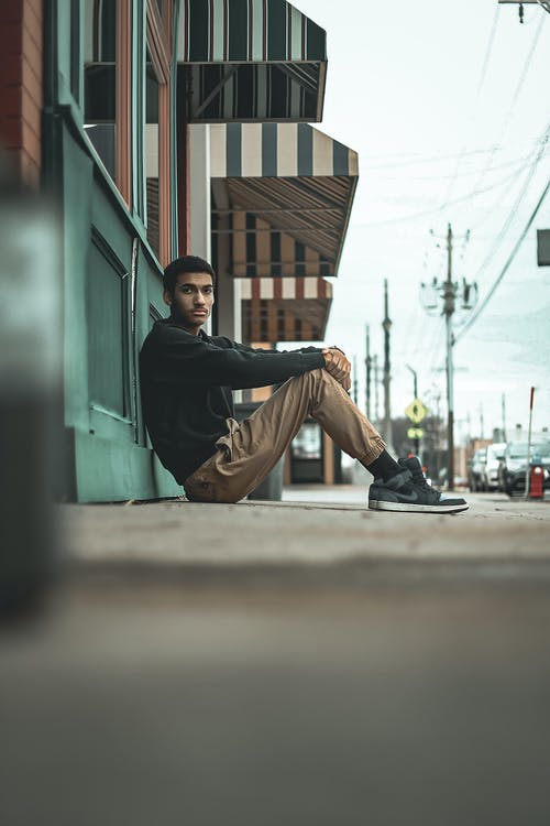 靠在墙上坐着的人的选择性聚焦摄影 · 免费素材图片