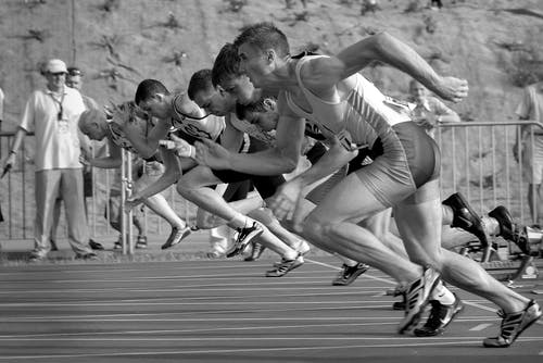 灰度摄影中田径椭圆上奔跑的运动员 · 免费素材图片