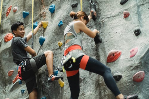 坚定的年轻族裔登山者在健身房安全带上升墙 · 免费素材图片