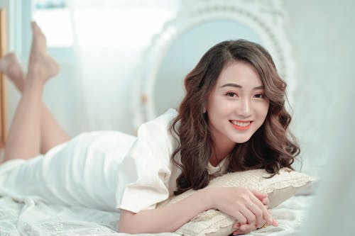 躺在床上摆姿势的微笑妇女的照片 · 免费素材图片