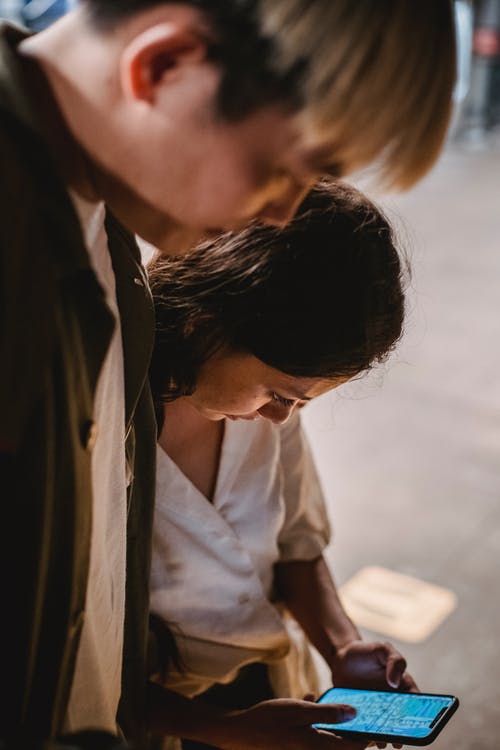 严重的族裔夫妇在智能手机上使用应用程序 · 免费素材图片