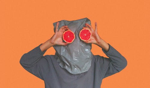 拿着切片的血橙时头部被塑料袋覆盖的人 · 免费素材图片