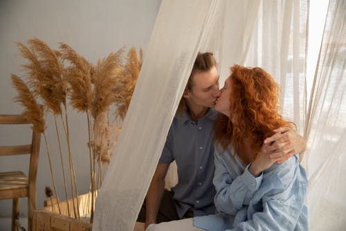 恩爱的夫妻在窗帘附近接吻 · 免费素材图片