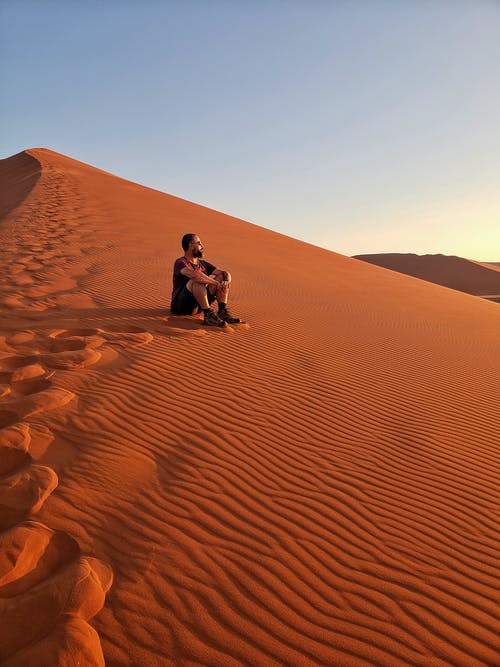 坐在沙漠上的男人 · 免费素材图片