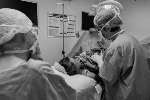 女人躺在医院的病床上的灰度照片 · 免费素材图片