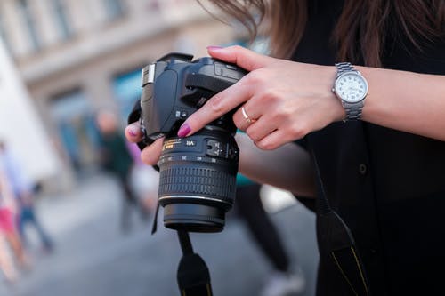 女人拿着黑色的数码单反相机 · 免费素材图片