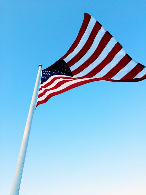 美国国旗在蓝蓝的天空下的杆子上 · 免费素材图片