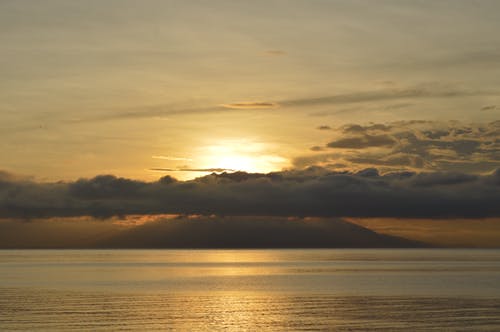 日落期间在平静的海面之上的云 · 免费素材图片