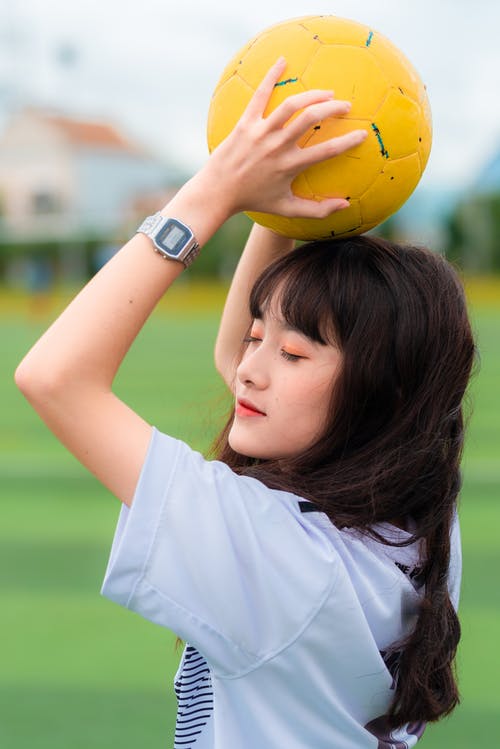 女人抱着黄色的足球 · 免费素材图片