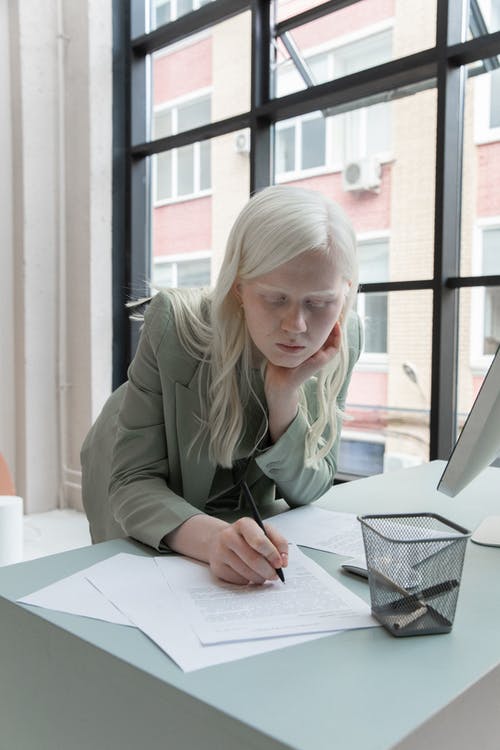 年轻的白化女商人在办公室写笔记 · 免费素材图片