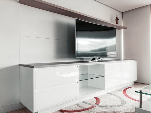 黑色的纯平电视，在白色的木制电视机架上 · 免费素材图片