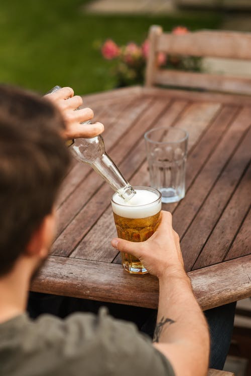 男性从瓶倒啤酒到玻璃器皿 · 免费素材图片