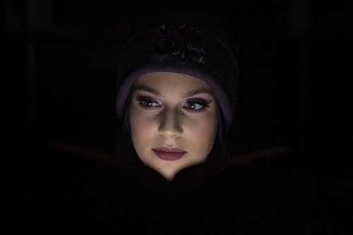 在黑暗中阅读时紫色豆豆的女人 · 免费素材图片