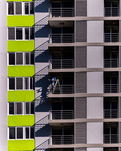 男子站在一座建筑的阳台上的梯子上 · 免费素材图片