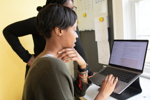在笔记本电脑上工作的灰色毛衣的女人 · 免费素材图片
