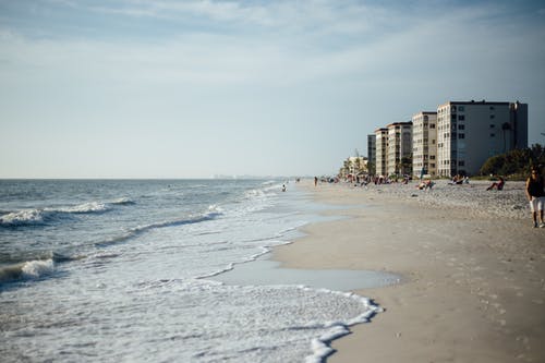 白天在海边与建筑物白多云的天空 · 免费素材图片