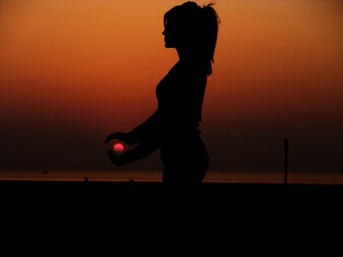 一个女人抱着太阳的剪影的力透视摄影 · 免费素材图片
