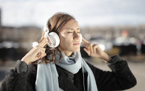 女人使用白色耳机的浅焦点照片 · 免费素材图片