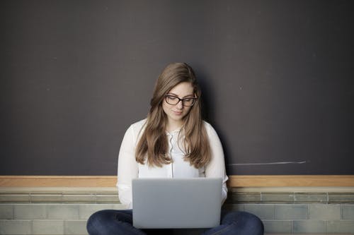 使用macbook的白色长袖衬衫和蓝色牛仔牛仔裤的女人 · 免费素材图片