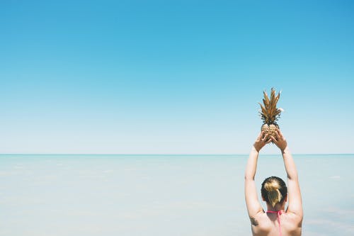 女人抱着菠萝水果站附近的水体 · 免费素材图片