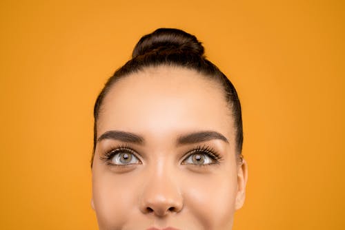女人的脸在橙色背景前的特写照片 · 免费素材图片