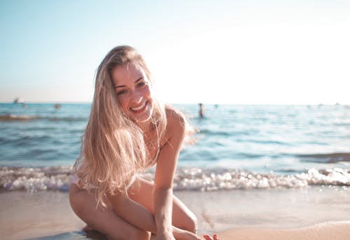 女人坐在海滩上的照片 · 免费素材图片