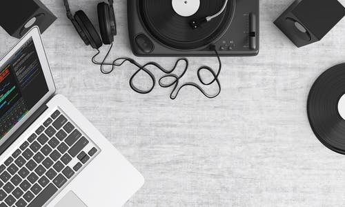 Macbook Pro在灰色桌子上的黑色耳机旁边 · 免费素材图片