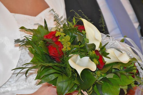 新娘抱着白马蹄莲百合和红玫瑰鲜花花束 · 免费素材图片