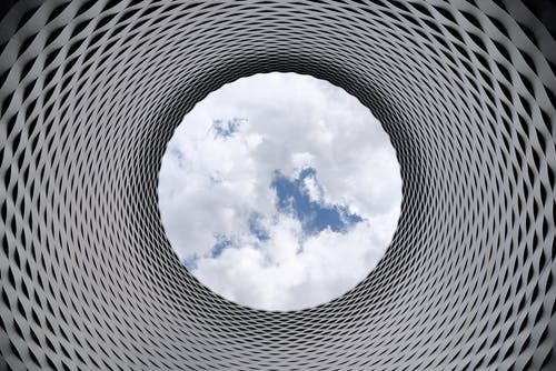 俯瞰白色多云和蓝天的灰色和黑色隧道的低角度摄影 · 免费素材图片