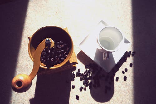 杯子旁边的棕色咖啡研磨机 · 免费素材图片