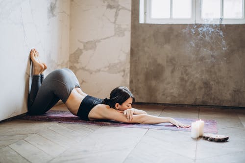 躺在瑜伽垫上做瑜伽的灰色紧身裤的女人 · 免费素材图片